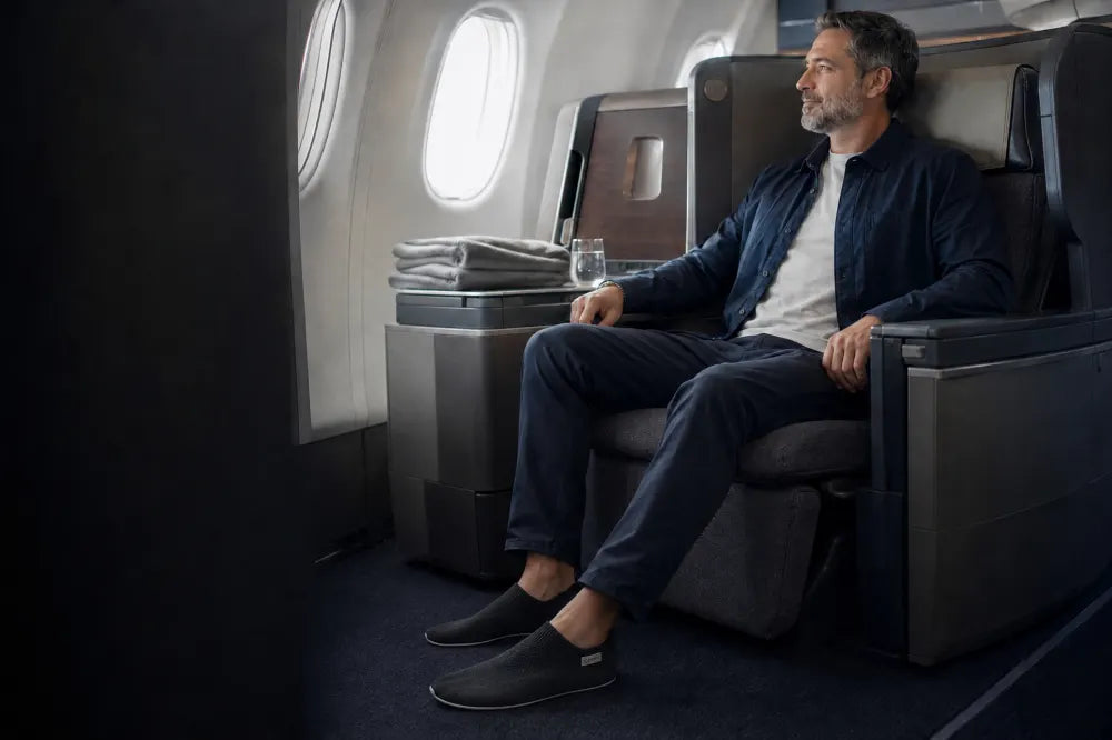 Traveler seated in first class wearing black COOPS Low Tops.