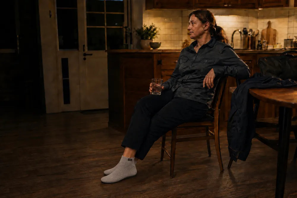 Woman resting on a chair at the end of a shift, wearing ash gray COOPS sock shoes.