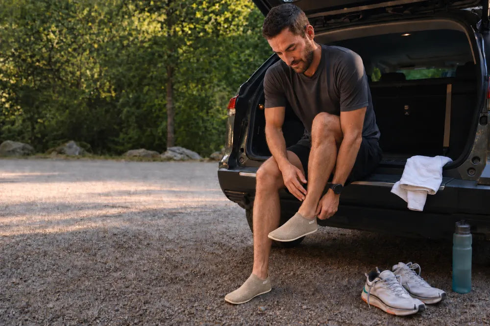 Runner changing into sand COOPS Low Tops at his car.