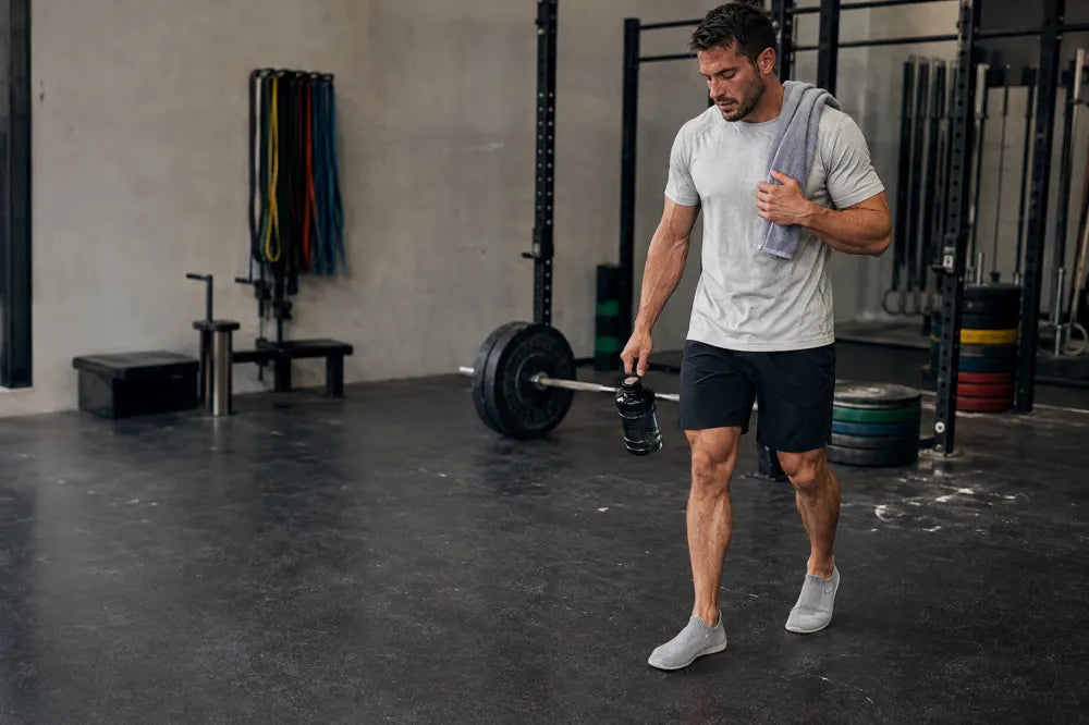 Athlete walking a gym floor in ash gray COOPS Low Tops.