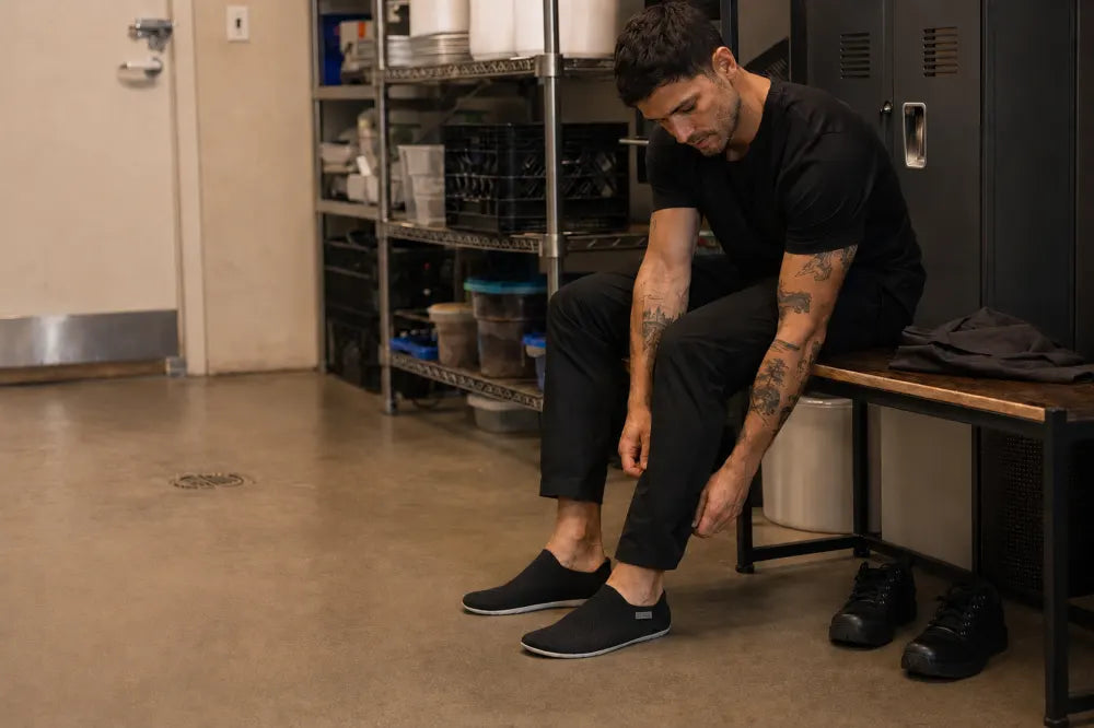 Hospitality worker changing into black COOPS Low Tops after close.