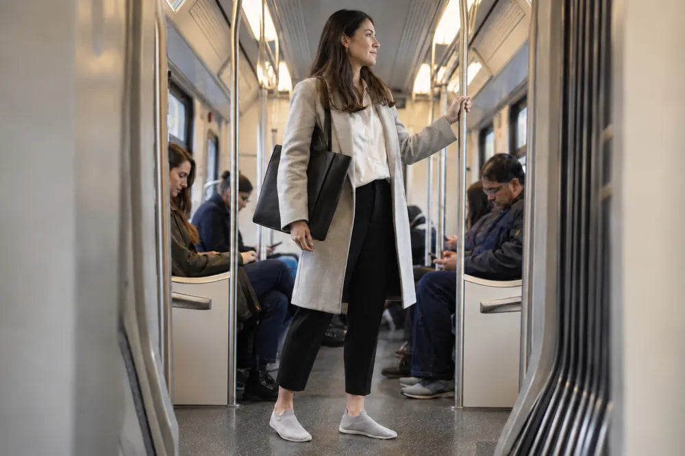 Commuter standing on a train in ash gray COOPS Low Tops.