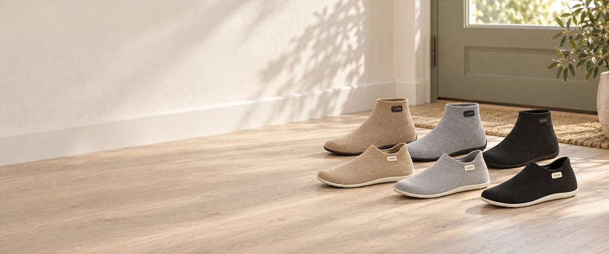 All six COOPS sock shoes, High Top and Low Top in Black, Ash Gray and Sand, lined up by the front door