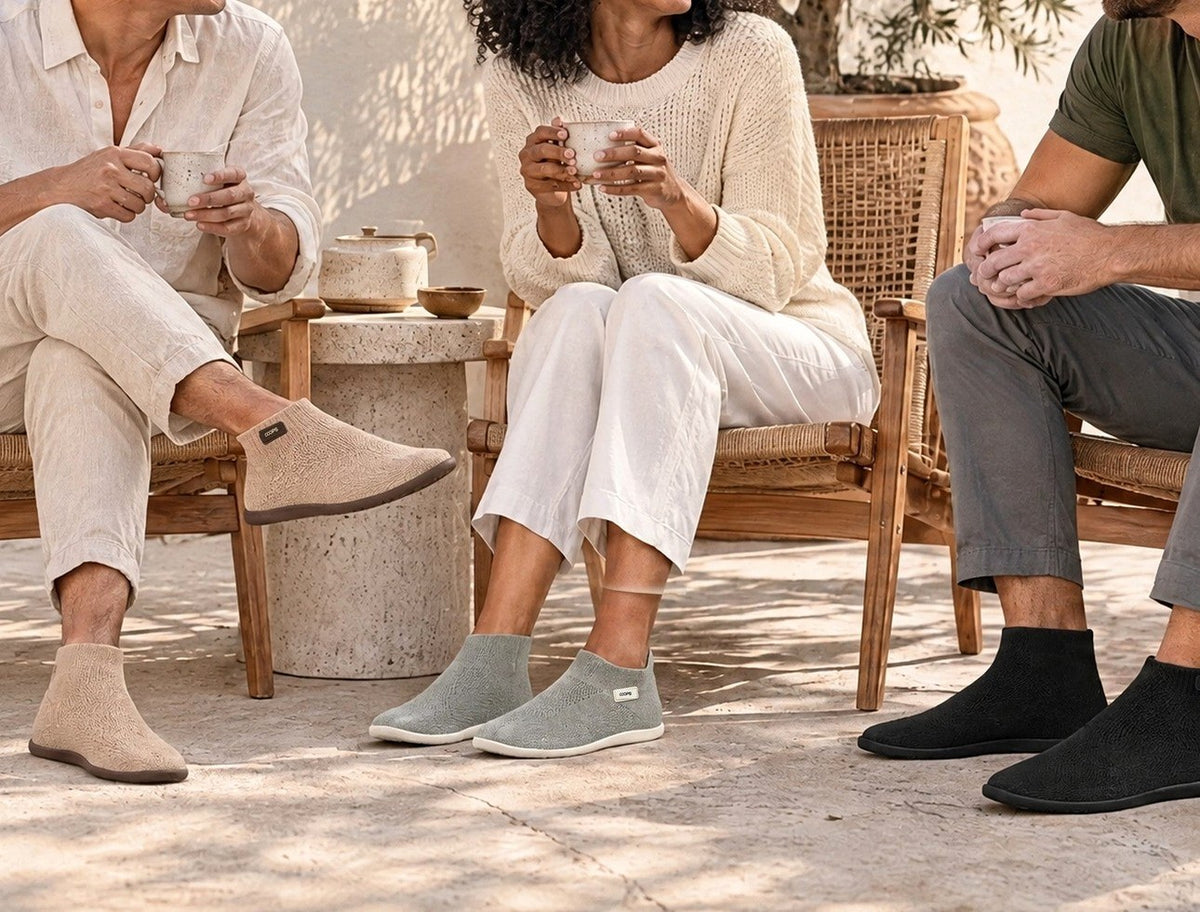 Three friends with coffee on a sunlit patio wearing Sand High Top, Ash Gray Low Top and Black High Top COOPS sock shoes