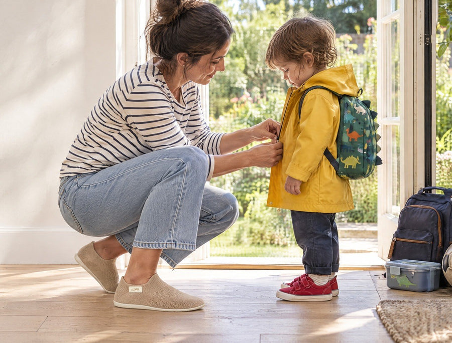 Parent with a coffee in a bright kitchen while a child eats breakfast, wearing Ash Gray COOPS Low Top sock shoes