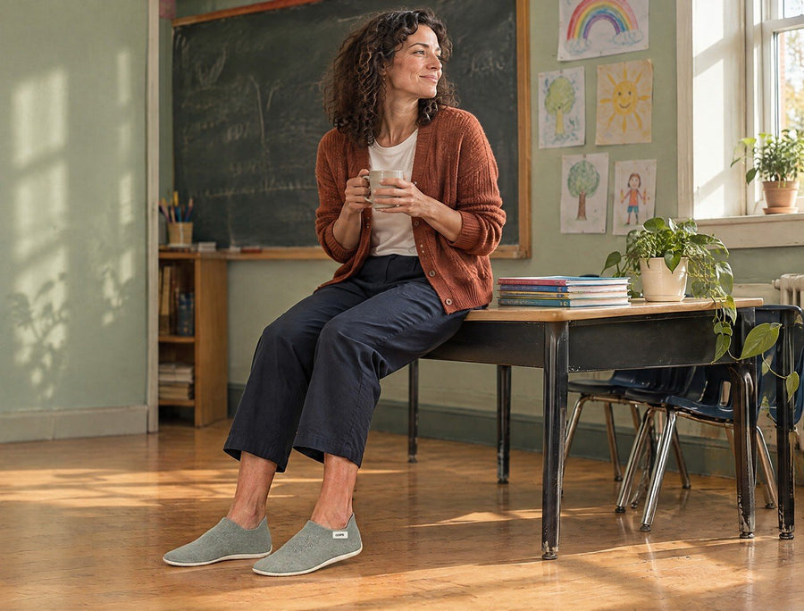 Enseignant assis sur un banc dans un couloir d’école après les cours, portant des chaussures-chaussettes COOPS Low Top noires