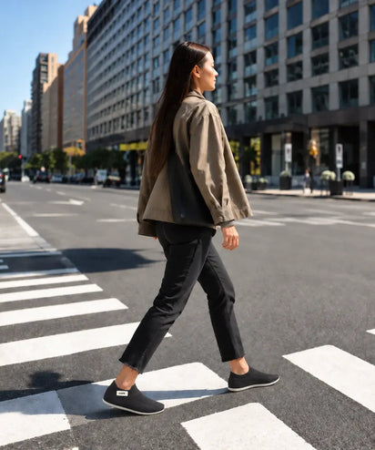 A woman crossing a city street in Black COOPS sock shoes