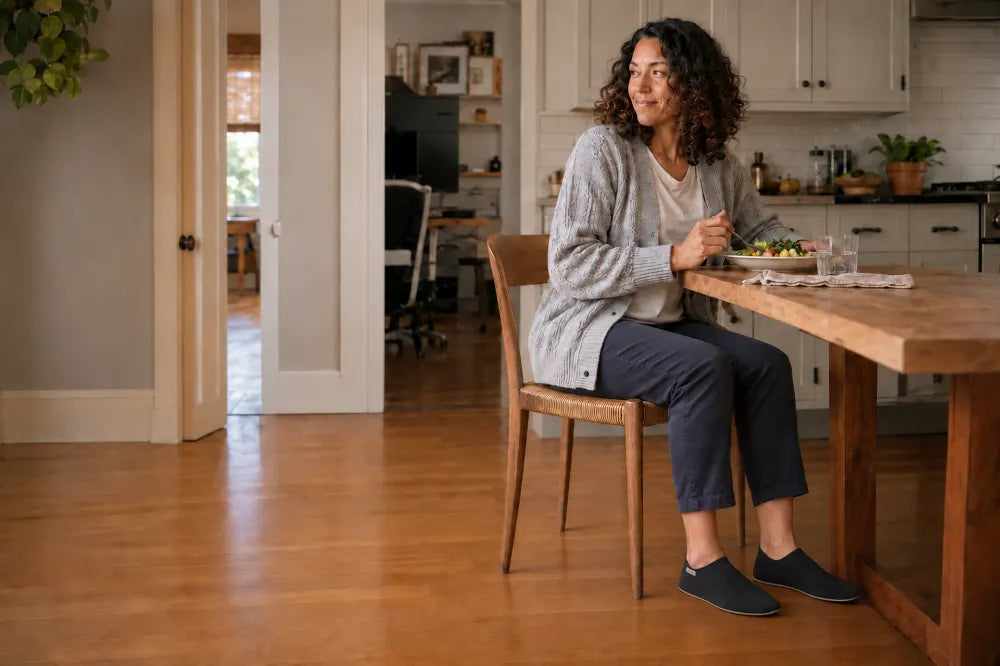 Woman eating lunch at her kitchen table wearing black COOPS Low Tops.