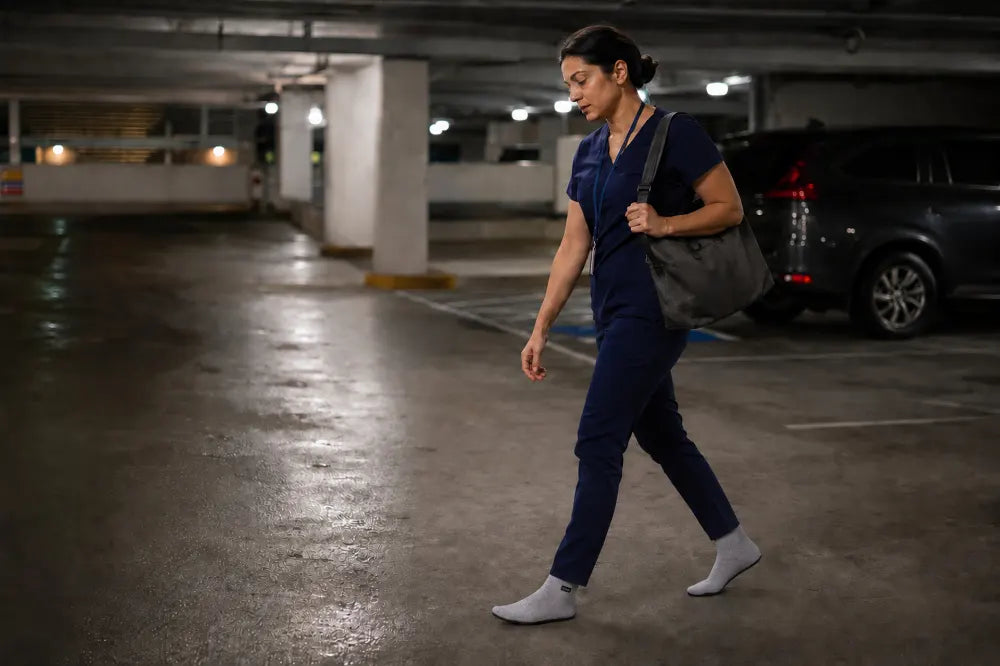 Nurse walking through a parking garage in ash gray COOPS High Tops.