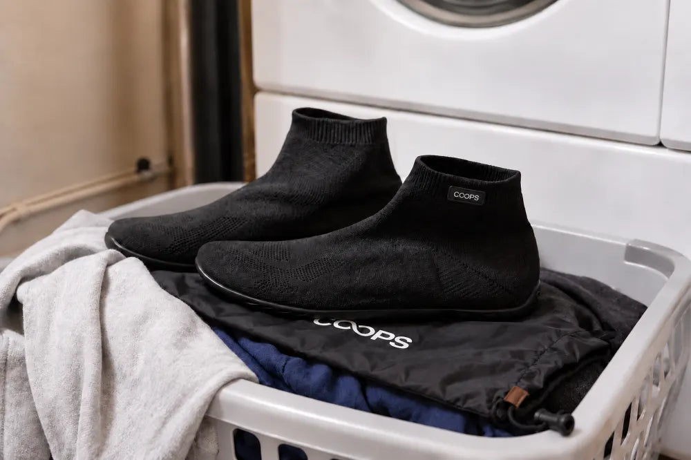 Black COOPS High Tops on a laundry basket in a dorm.