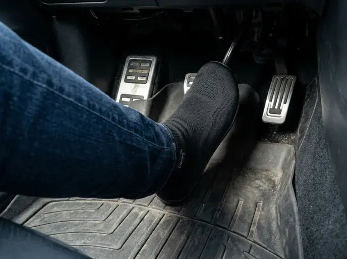 Driver’s feet on car pedals in Black COOPS sock shoes